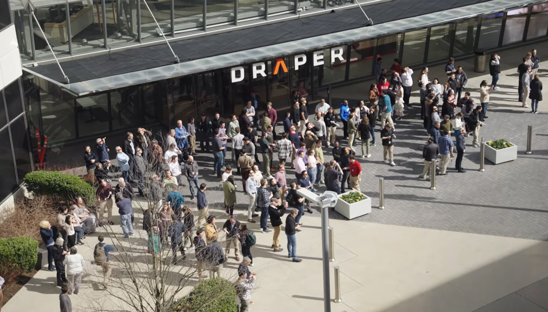Draper employees gathered outside the Cambridge headquarters beneath the wordmark