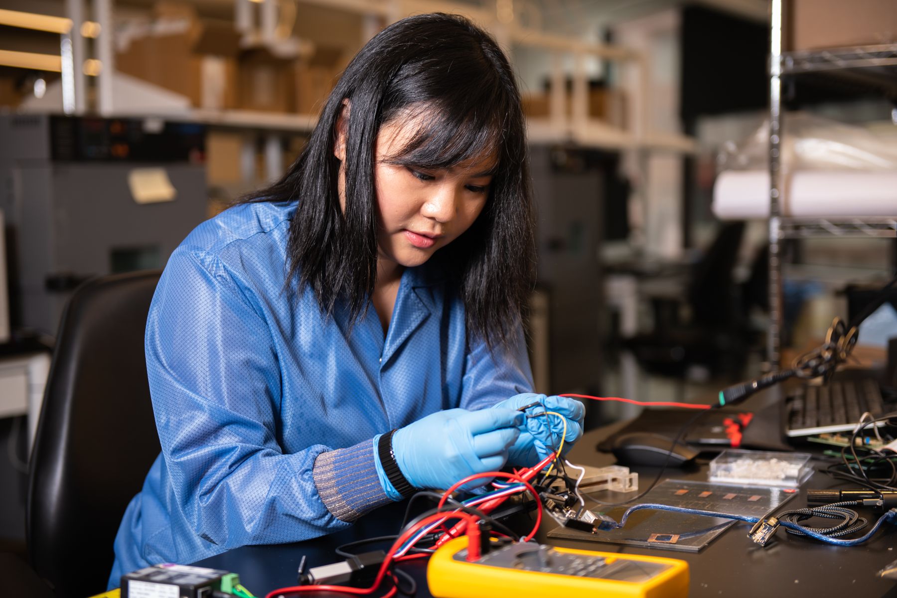 A Draper engineer probing a wired assembly at an electronics bench