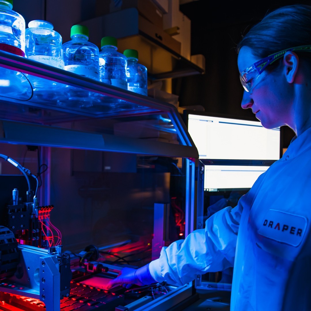 A Draper researcher operating a microfluidic instrument in the lab